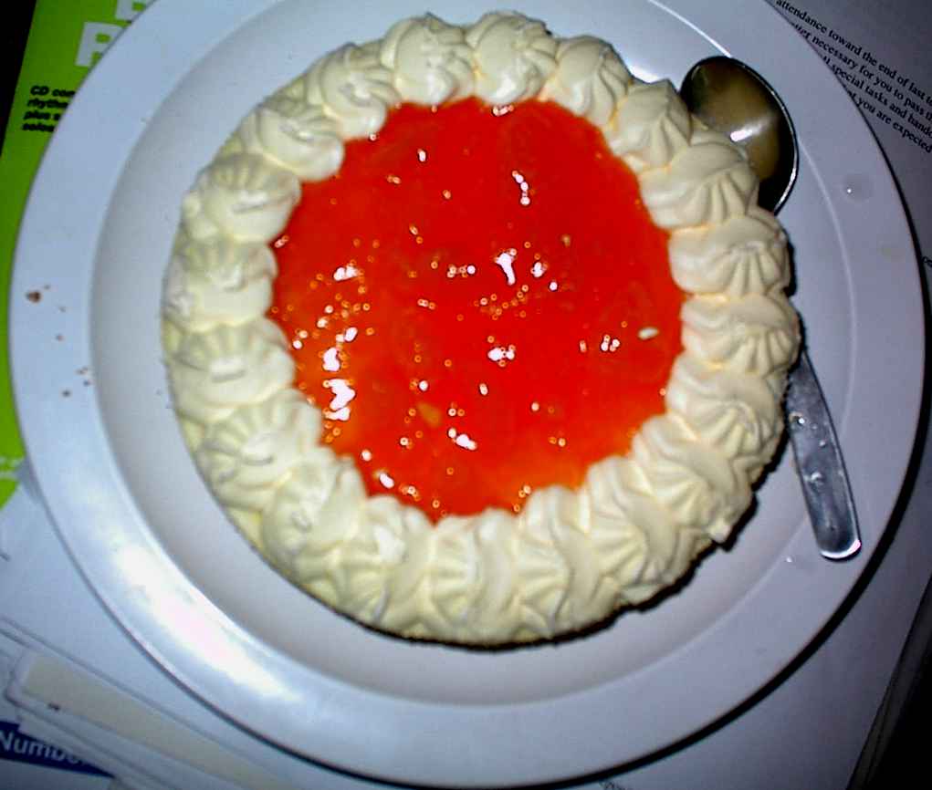A photograph of an iced cake with red fruit.