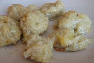 A plate of roughly rounded, pale dumplings with golden patches.