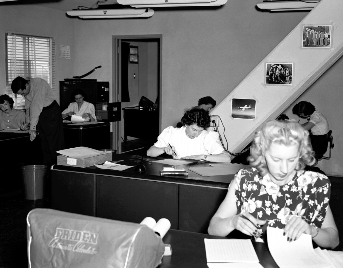 Black-and-white photograph of a woman working at a large computer in a computer room, captioned Computer room in 1949.