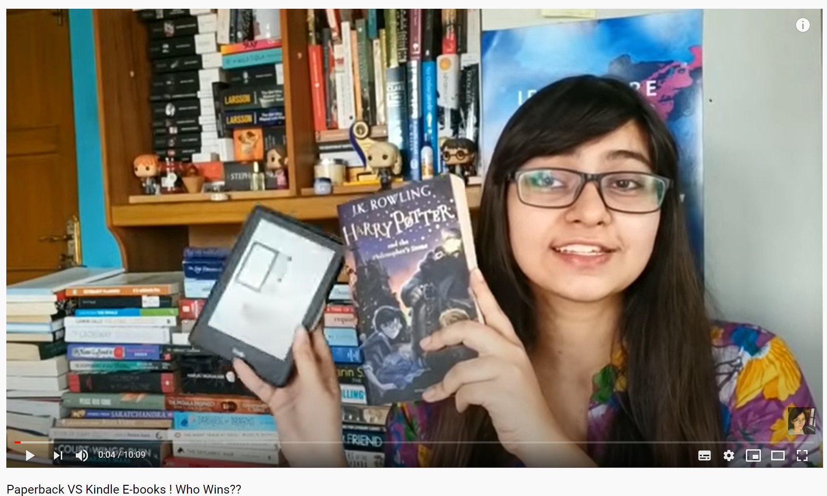 Screenshot of a YouTube video titled “Paperback VS Kindle E-books ! Who Wins??”: a woman holding up an e-reader and a paperback Harry Potter book in front of bookshelves.