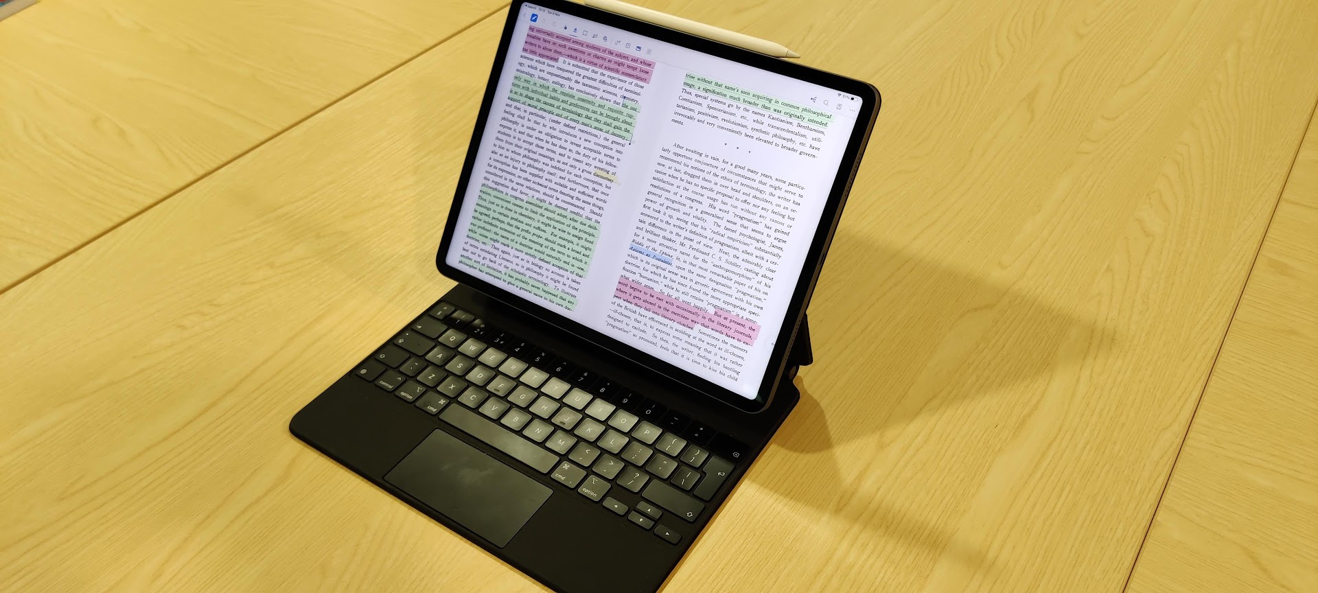 Photograph of an iPad with a keyboard case, showing a document with passages highlighted in several colours.