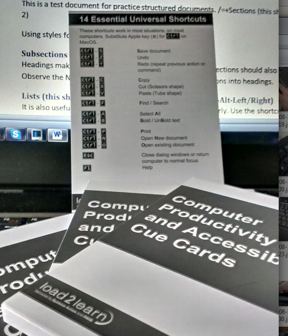 Printed Computer Productivity and Accessibility Cue Cards and a 14 Essential Universal Shortcuts reference card in front of a computer.