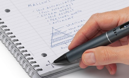 A hand using a digital pen on a spiral notebook containing handwritten notes and a pyramid sketch.