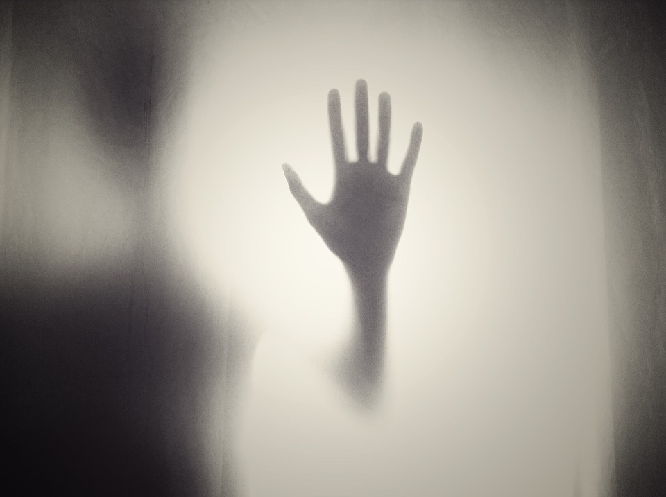 Blurred photograph of a hand pressed against frosted glass.