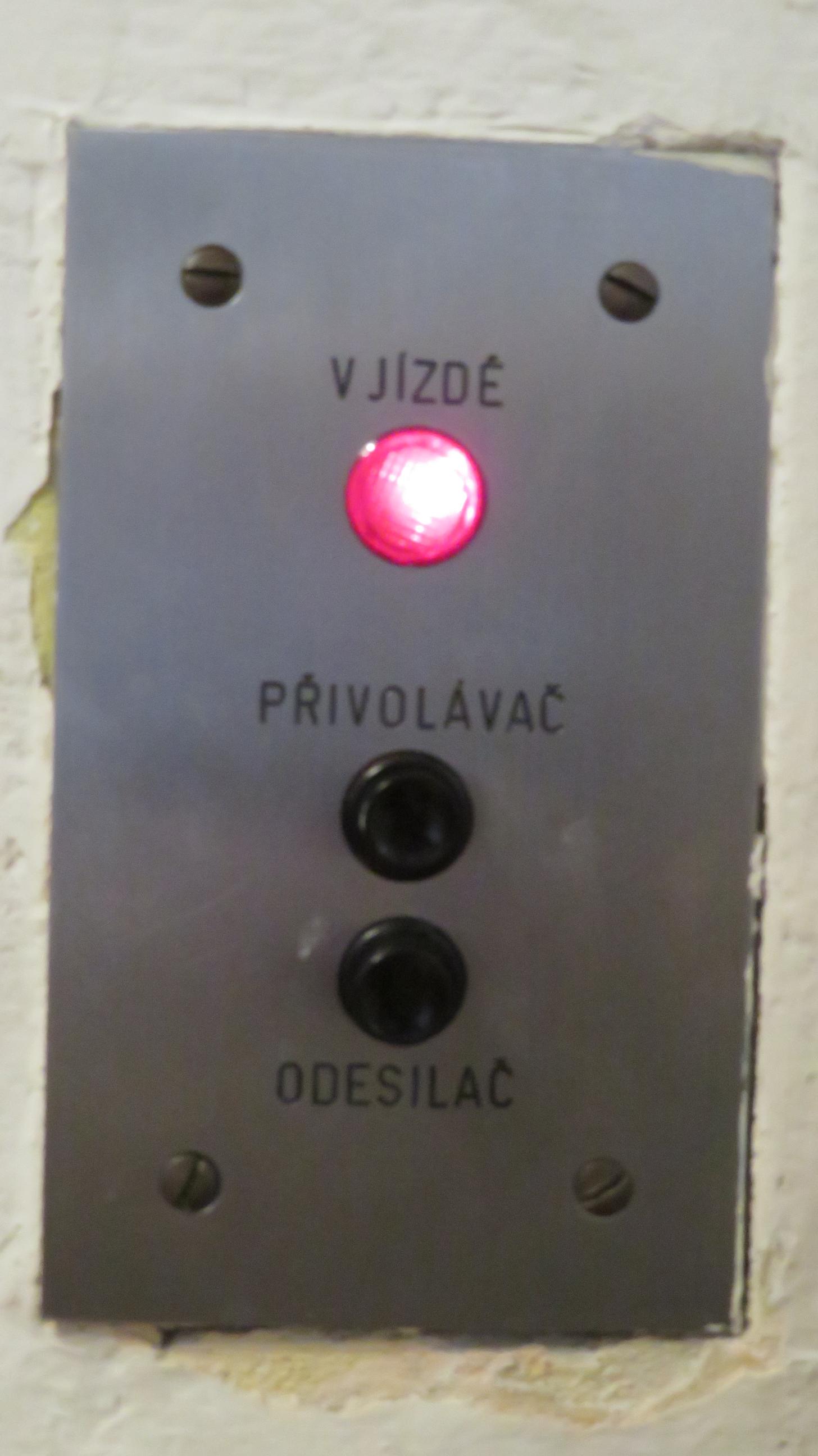 Photograph of two lift buttons: a green button with an upward arrow above a red button with a downward arrow.
