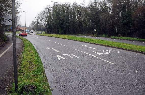Photograph of a road with white lettering and a line painted on the tarmac.